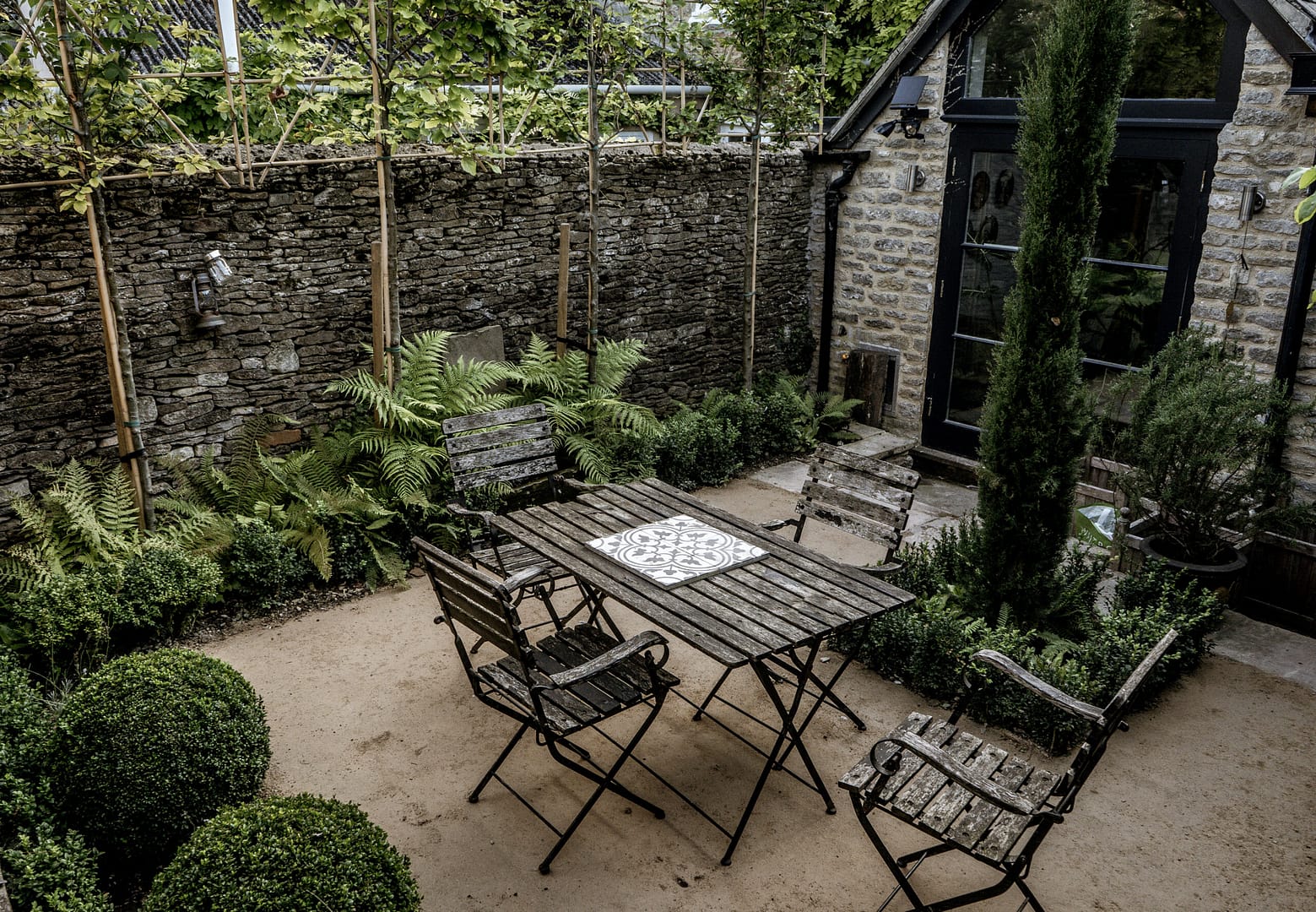 Cotswold evergreen shade garden with bench, buxus, ferns and cypress tree