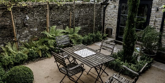 Cotswold evergreen shade garden with bench, buxus, ferns and cypress tree